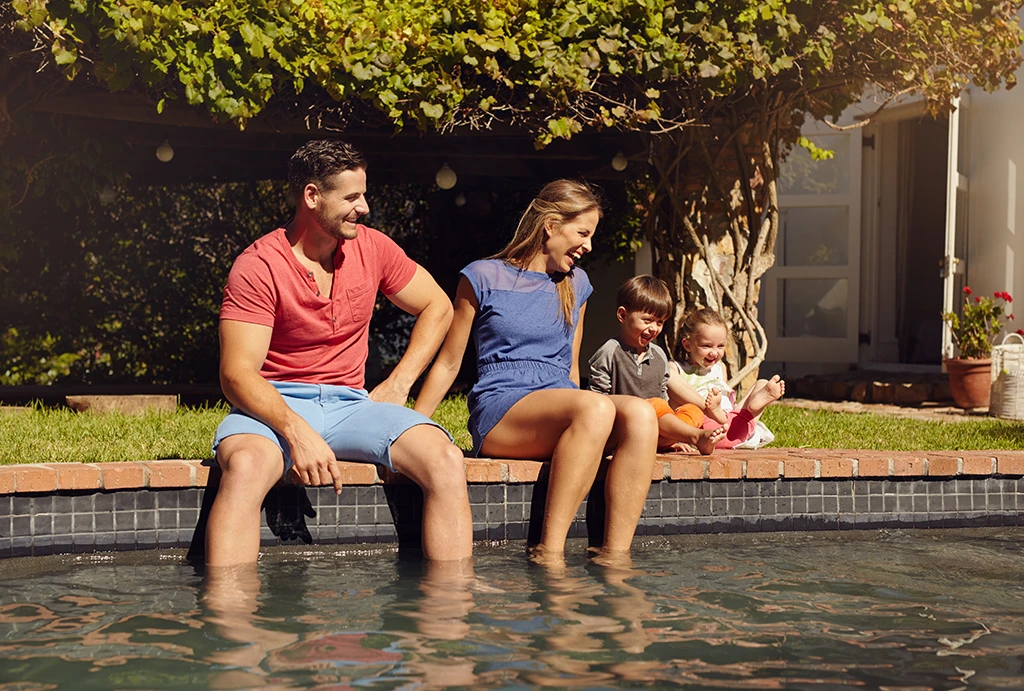 family-at-the-pool young family sitting on the poolside